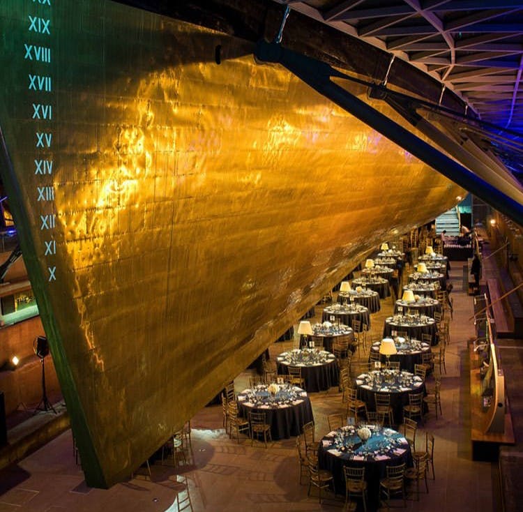 Elegant event space in The Dry Berth, Cutty Sark with golden structure and soft lighting.