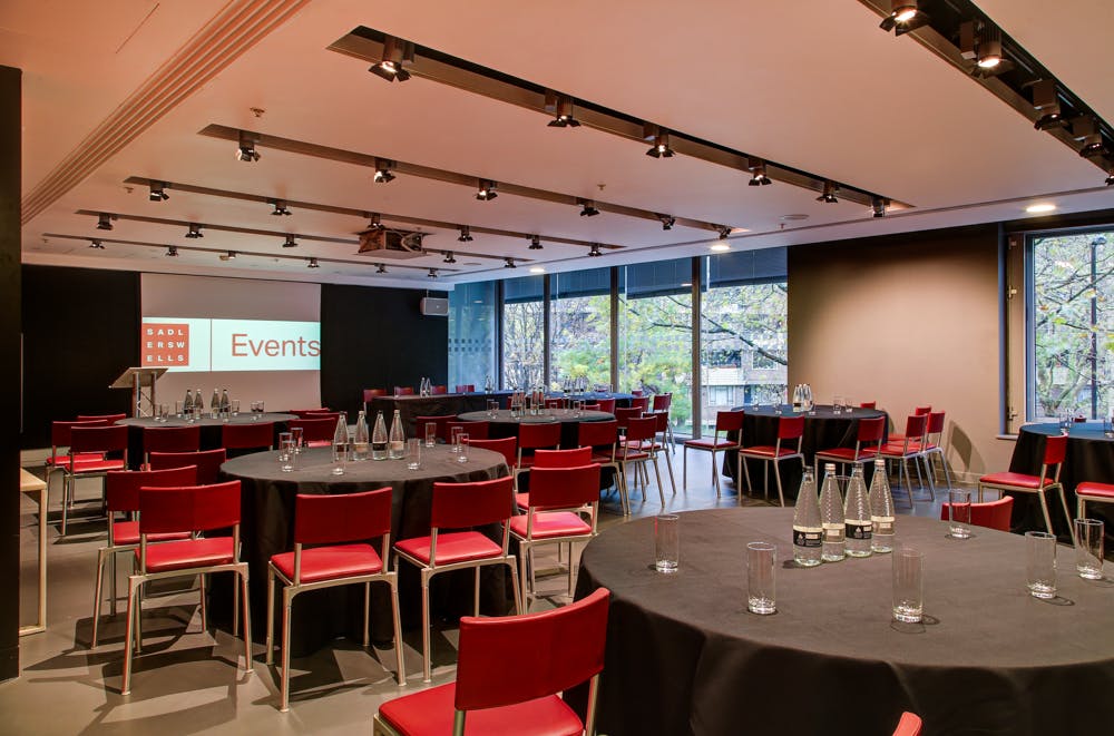 Dorfman Room at Sadler's Wells, set for meetings with round tables and red chairs.