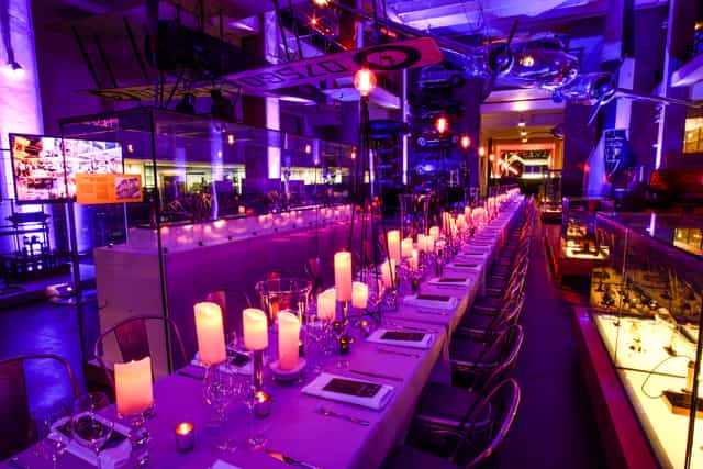 Elegant dinner setup in Science Museum, featuring vintage cars for corporate events.