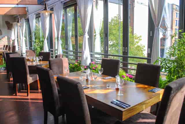 Sun-drenched On Bar dining space with lush greenery for corporate events and networking.