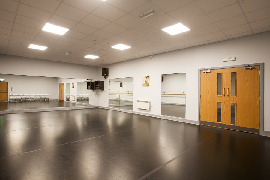 Versatile dance studio with polished floors and natural light for workshops and fitness classes.