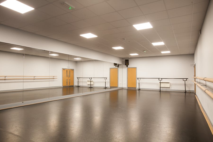 Spacious dance studio with mirrors and ballet bars for workshops and team-building events.