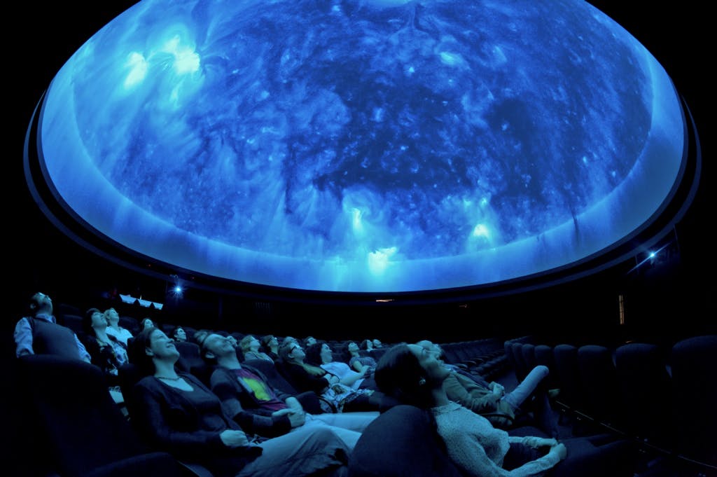 Audience captivated by celestial display in Peter Harrison Planetarium event venue.