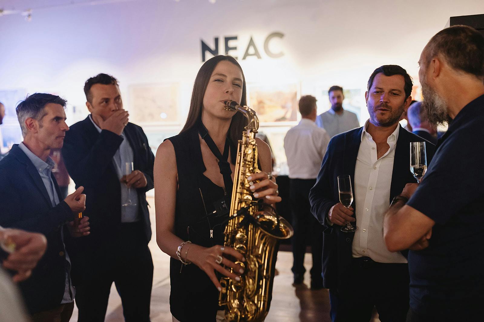 Vibrant networking event in West Gallery with live saxophone music and art displays.