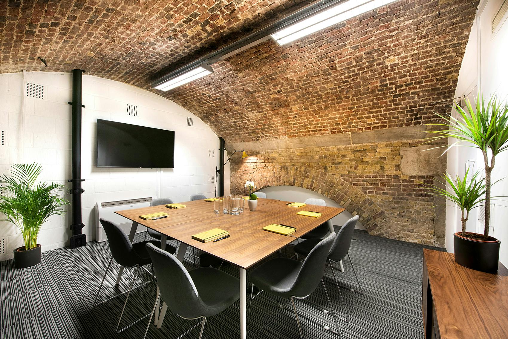 Modern meeting room with arched brick ceiling, perfect for workshops and presentations.