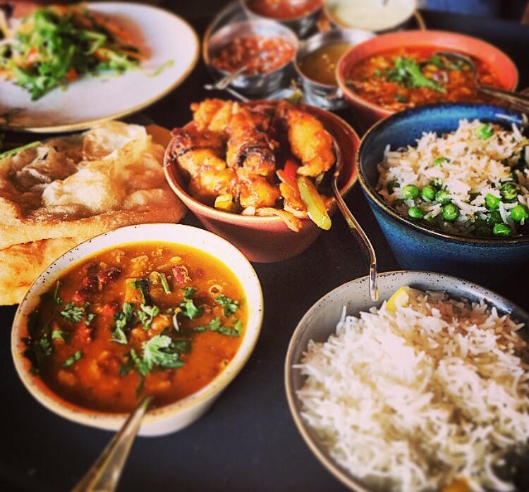 Vibrant Indian street kitchen catering spread with colorful curries and rice dishes.