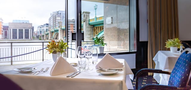 Elegant dining table by waterfront window at Little Ship Club for upscale events.