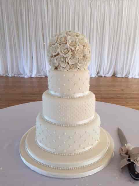 Elegant three-tier wedding cake with floral topper in The Britannia Suite, Ravens Ait Island.