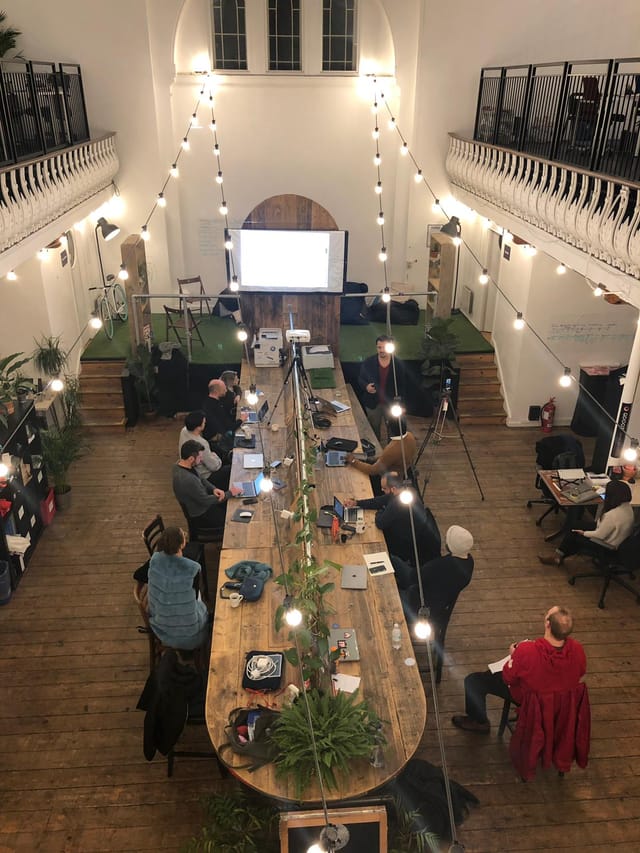 Collaborative meeting space at Launch22 King's Cross with wooden table and projector.