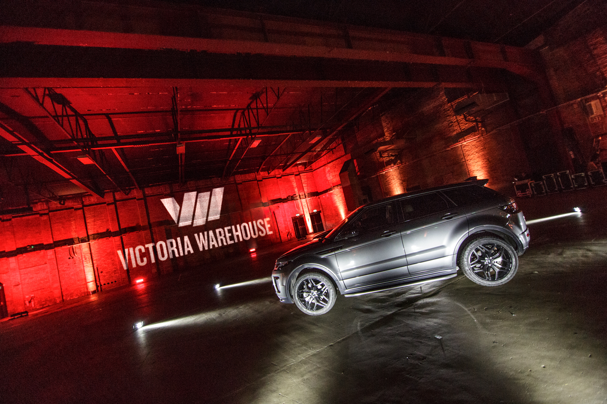 Event setup at Victoria Warehouse with dramatic lighting and sleek vehicle for product launch. - Banner