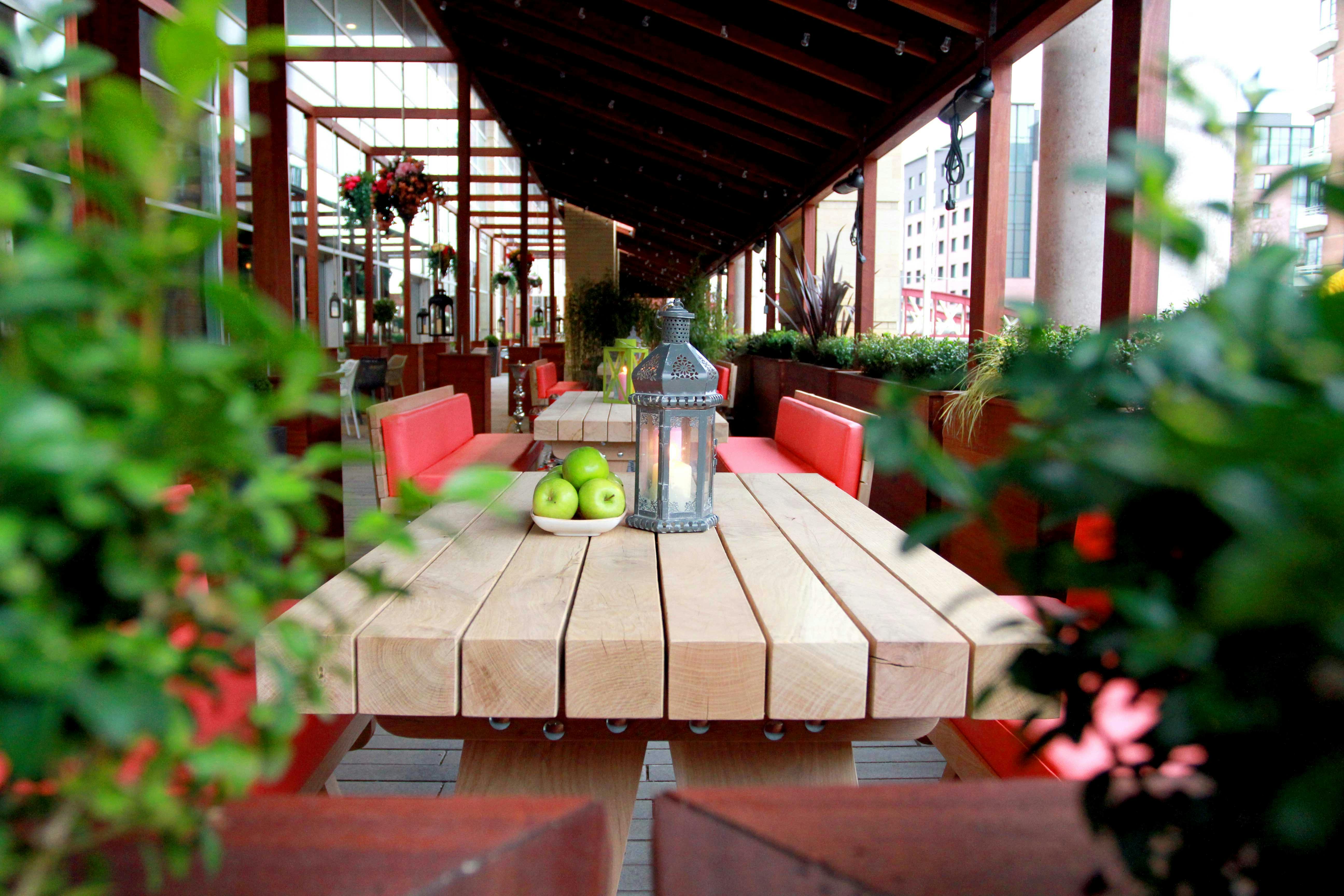 Outdoor meeting space with wooden table, greenery, ideal for corporate retreats and social events.