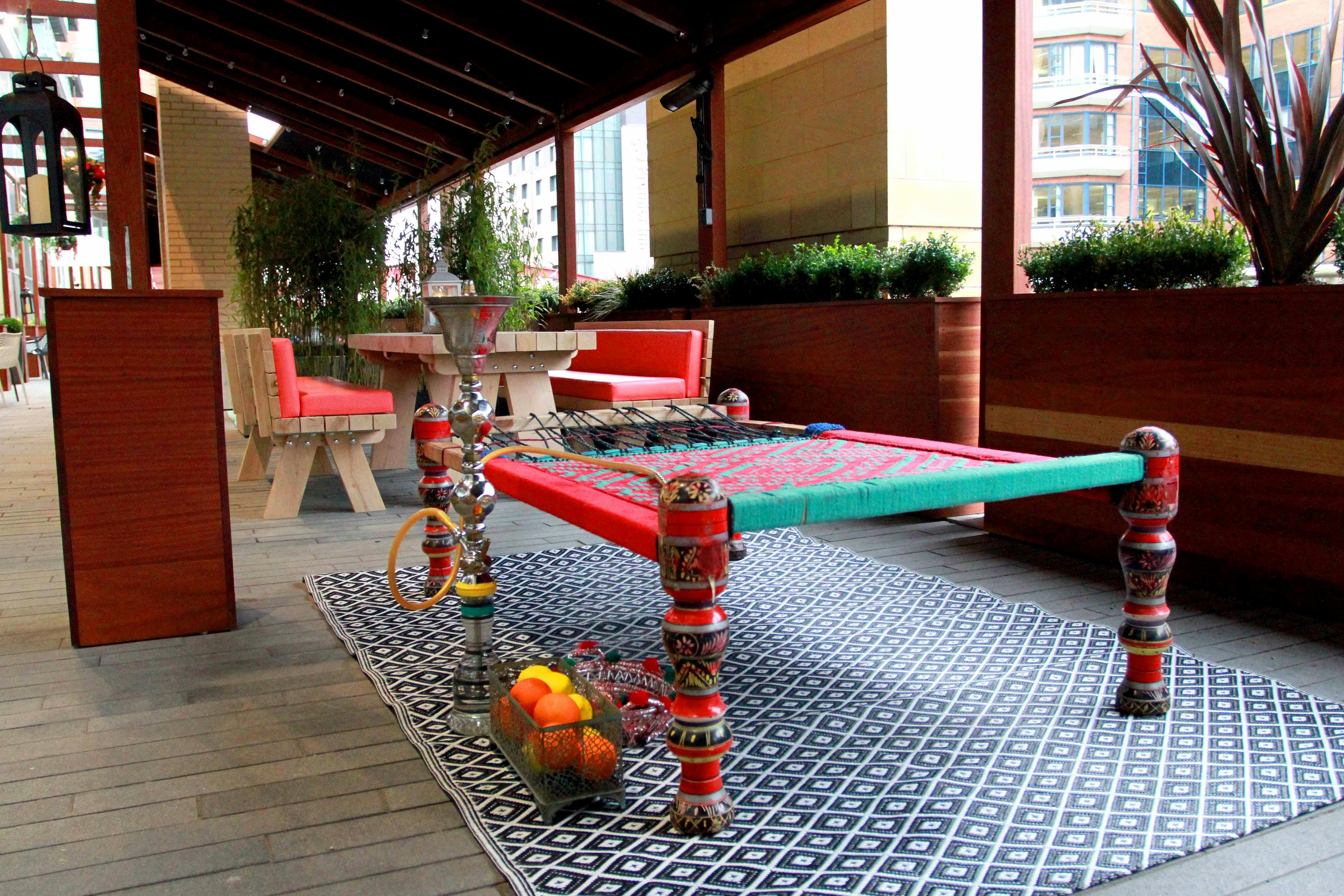 Vibrant outdoor event space with traditional Indian charpoy for cultural gatherings.