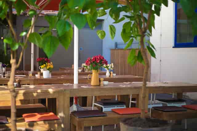 Charming outdoor dining at The Table Cafe with rustic tables and floral decor.