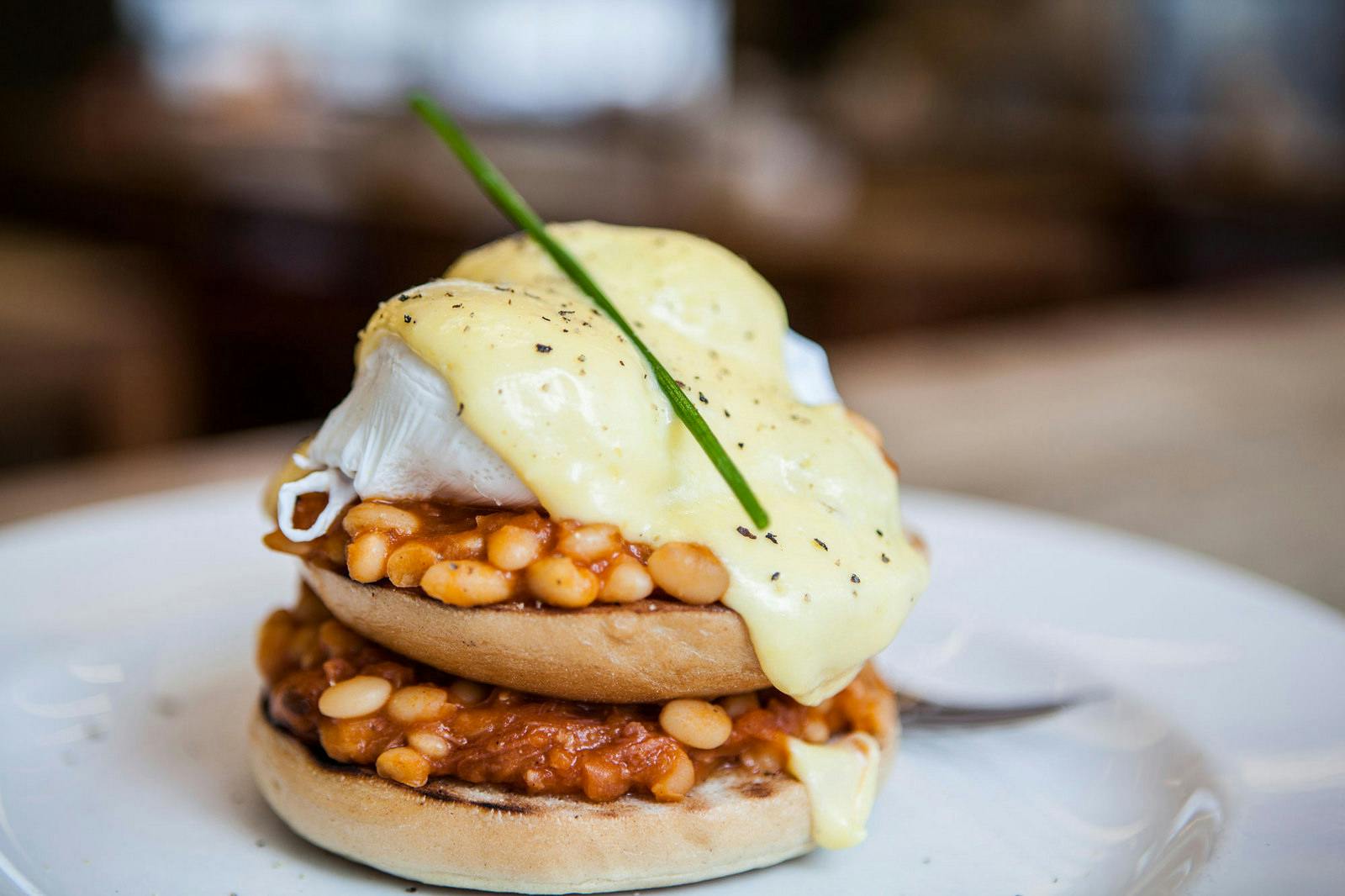 Poached eggs on baked beans and muffin at The Table Cafe for brunch events.