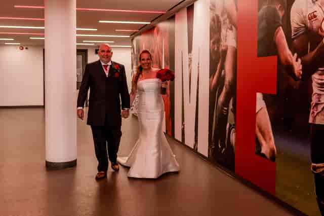 Couple in elegant attire walking through Players' Tunnel at Twickenham wedding venue.