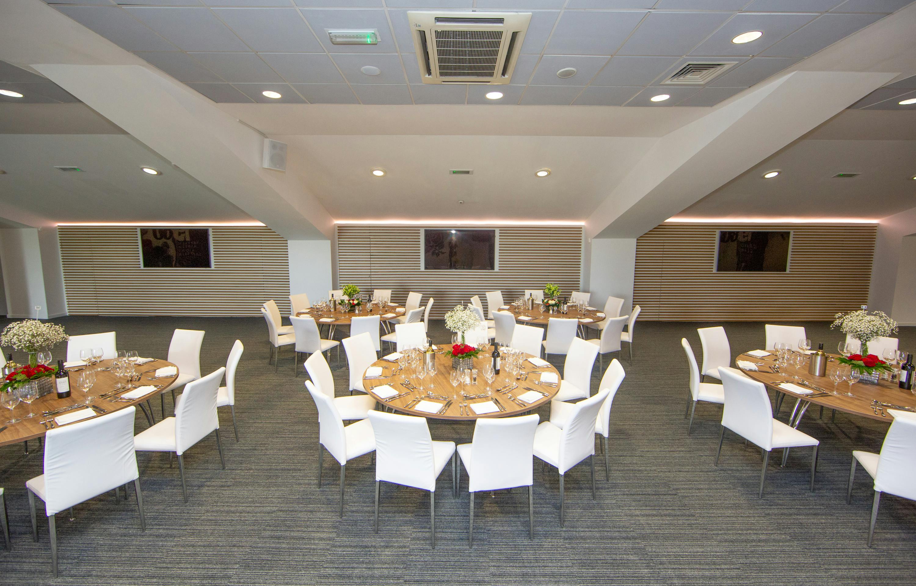 Beaumont event space at Allianz Stadium with round tables and floral centerpieces.