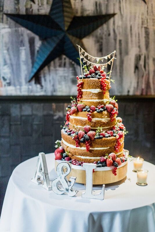 Multi-tiered wedding cake with berries and greenery at Balfour St Bart's venue. - Banner