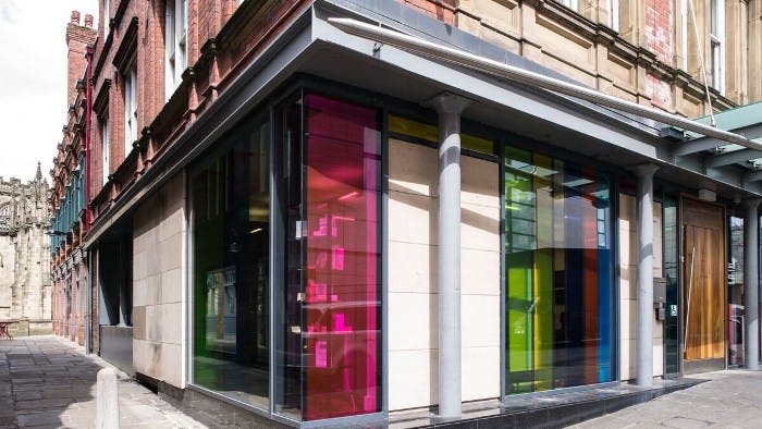 Modern conference space with vibrant glass panels at Manchester Cathedral Visitor Centre.