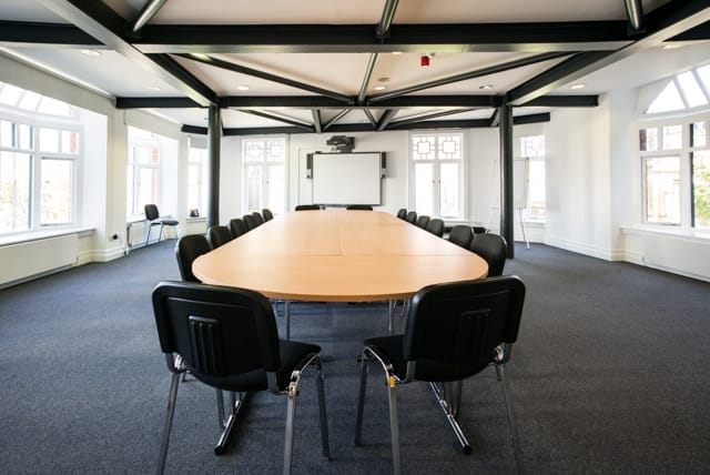 Spacious conference room with oval table at Manchester Cathedral Visitor Centre for meetings.