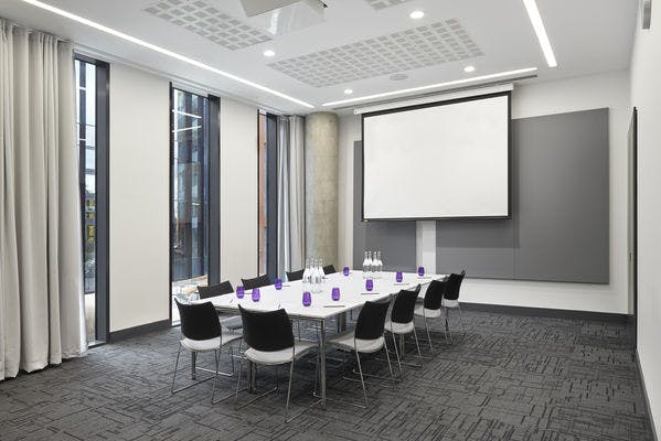 Modern meeting room at INNSIDE Manchester with long table, ideal for workshops and conferences.