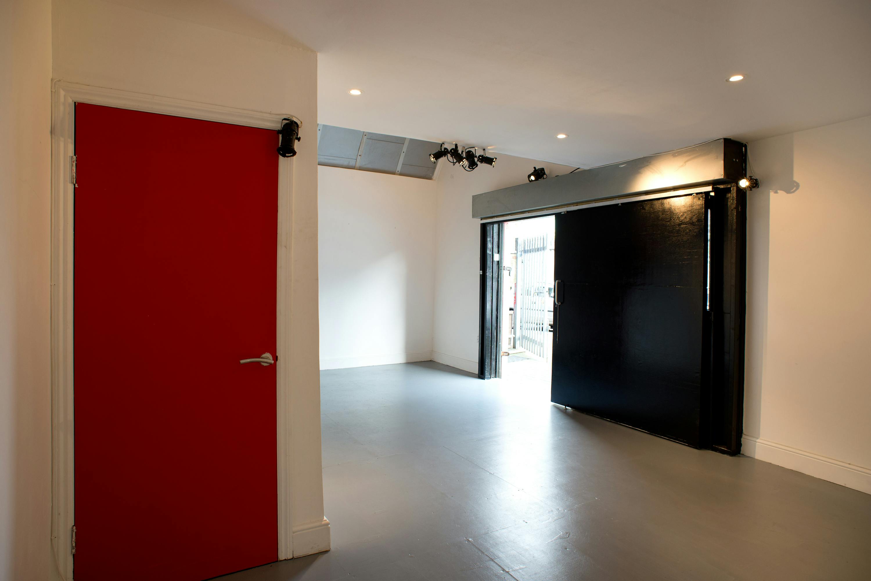 Versatile event space in Samurai Creative Hub with natural light and red door, perfect for workshops.