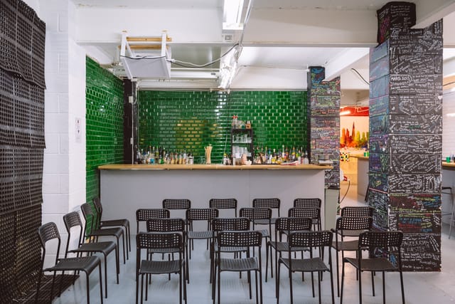 Main Room at London Bartender School with green bar, ideal for workshops and receptions.
