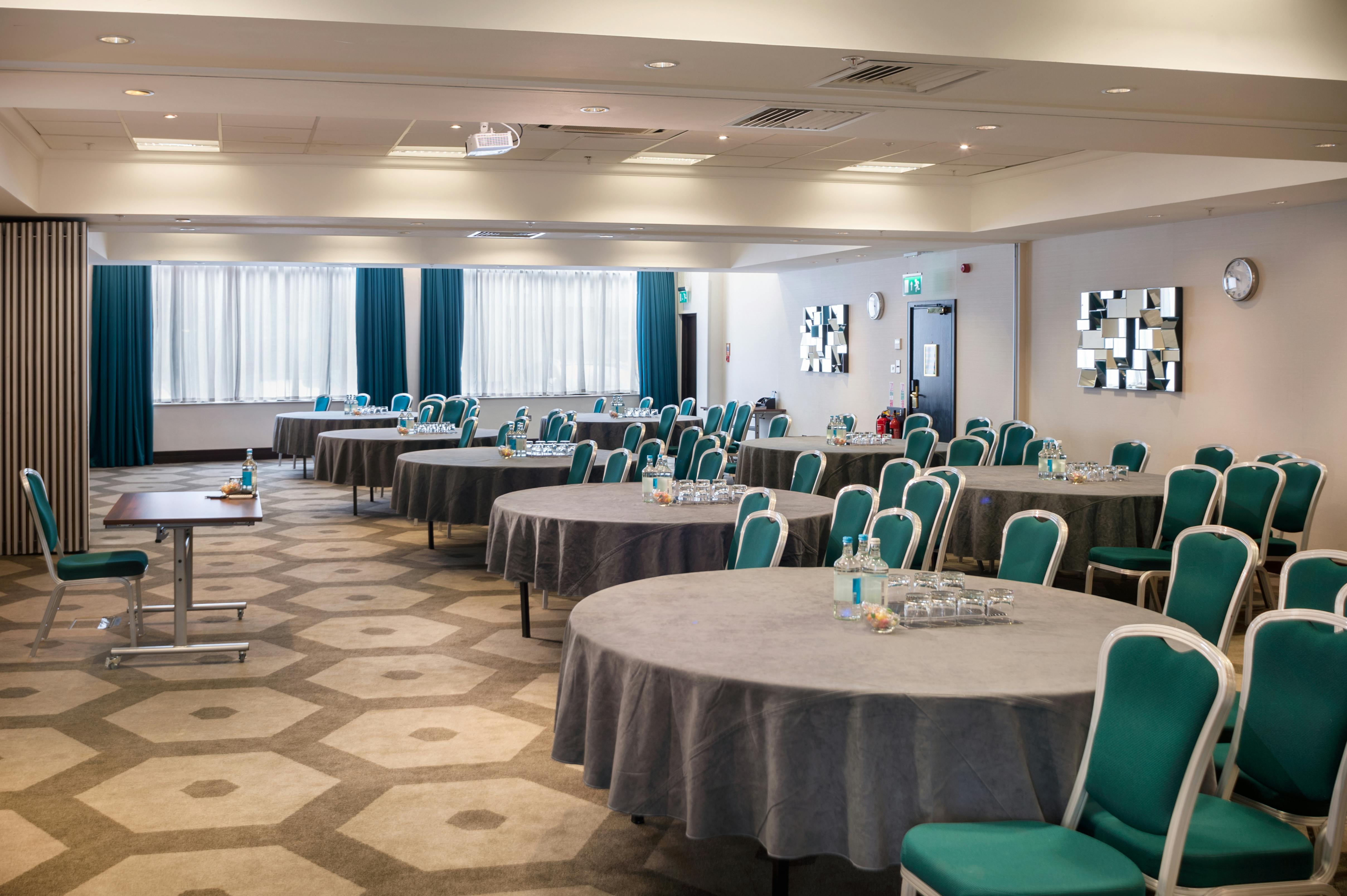 Pembroke Suite at Hilton London Olympia, bright meeting space with round tables for conferences.