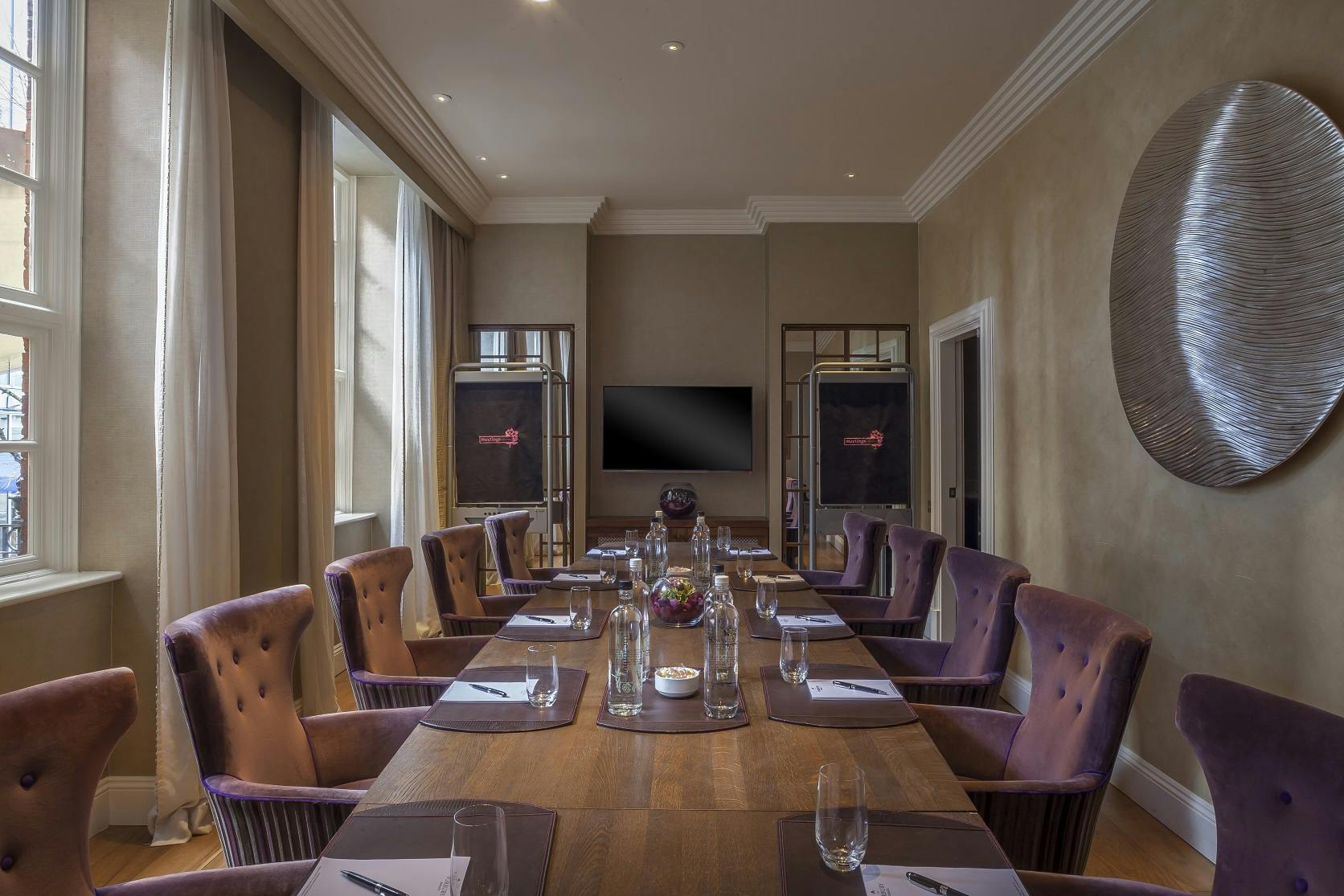 Sophisticated meeting room with wooden table and purple chairs at The Roseate, Reading.