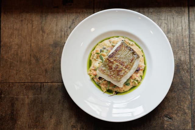 Plated fish with risotto at Bleeding Heart for events and culinary excellence.