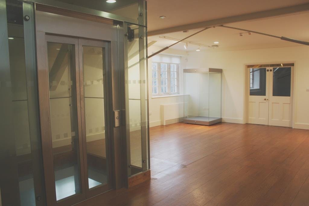 Alt text: Modern glass event space with wooden flooring at The Stables, Aston Hall for gatherings.