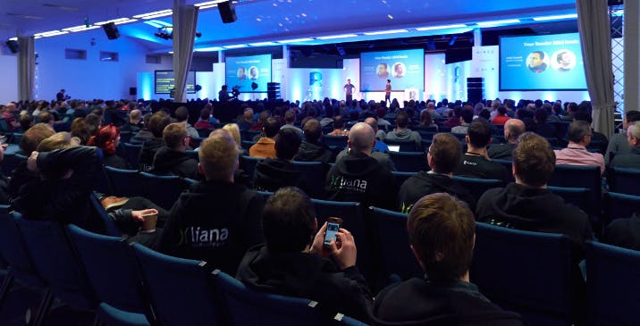 Thames Hall conference with engaged audience, modern venue, blue lighting, event design.