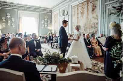 Elegant wedding ceremony at Leeds Castle's dining room with ornate decor.