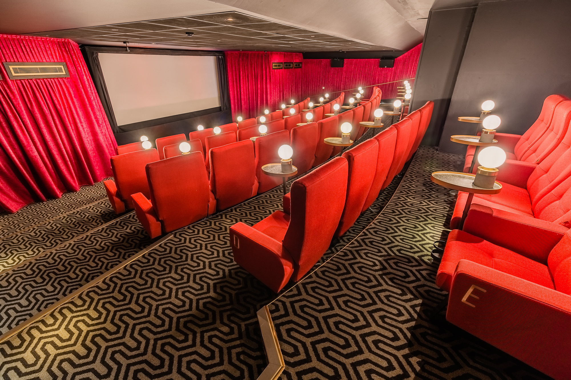 Intimate screening room with plush red seating for film screenings and corporate events. - Banner