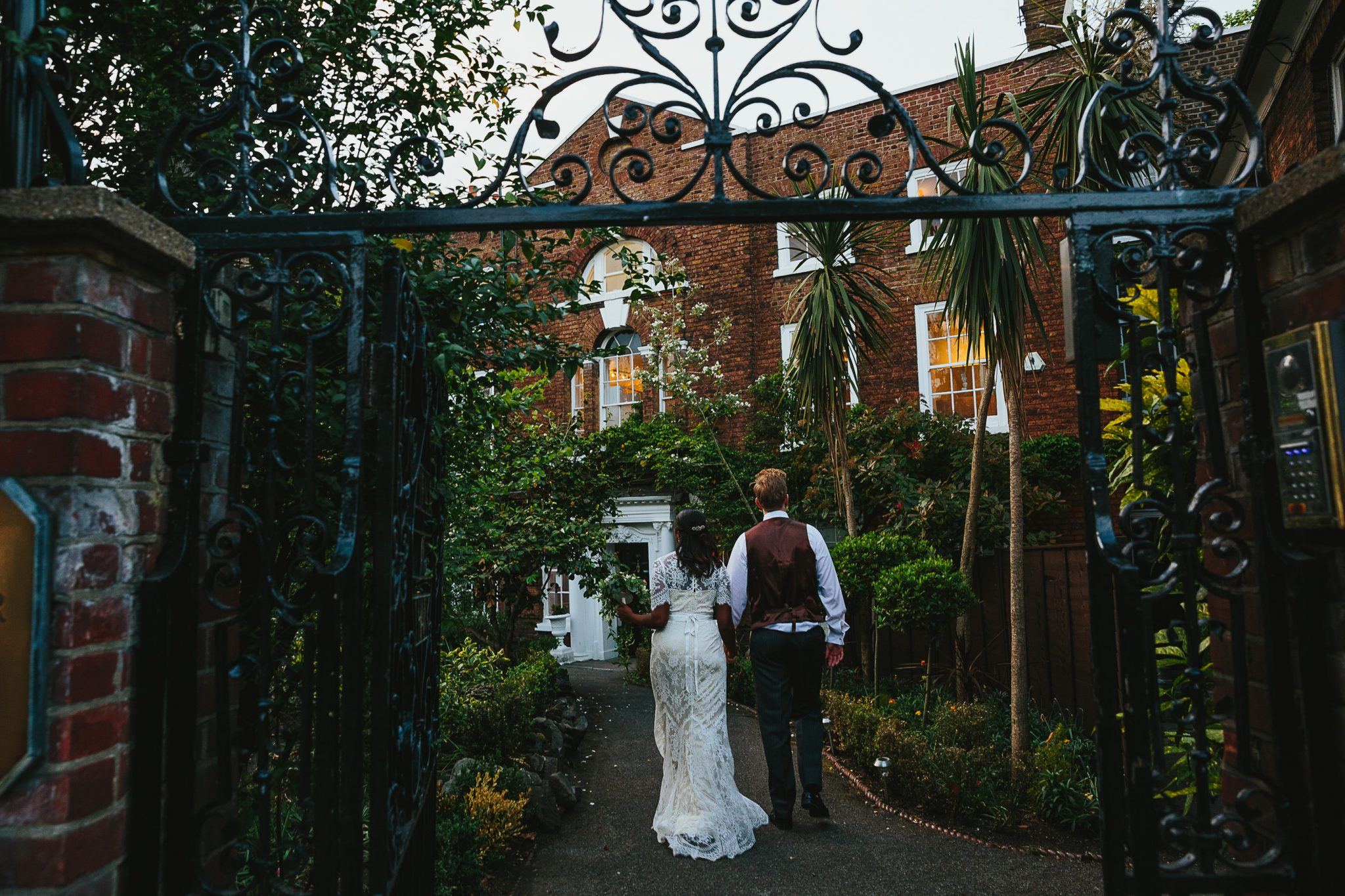 Couple walking through ornate gate at romantic Winchester House event venue. - Banner