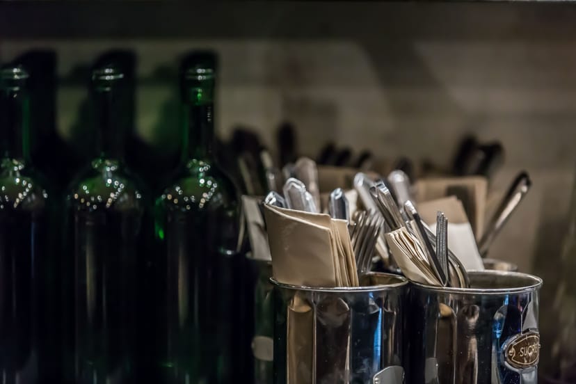Well-organized basement event setup with polished cutlery and glass bottles for quality service.