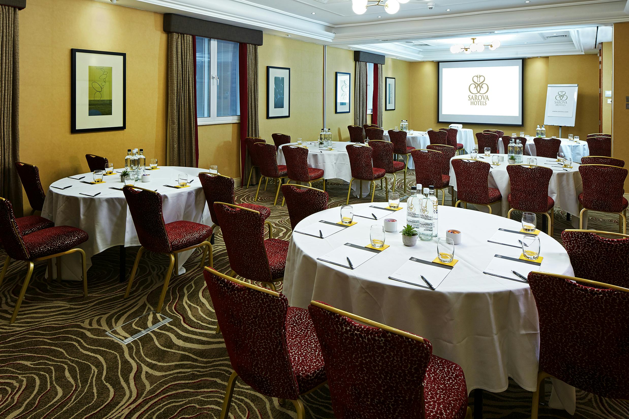 Queens Suite meeting room with circular tables, ideal for professional events and presentations.