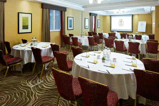 Queens Suite meeting room with circular tables, ideal for professional events and networking.