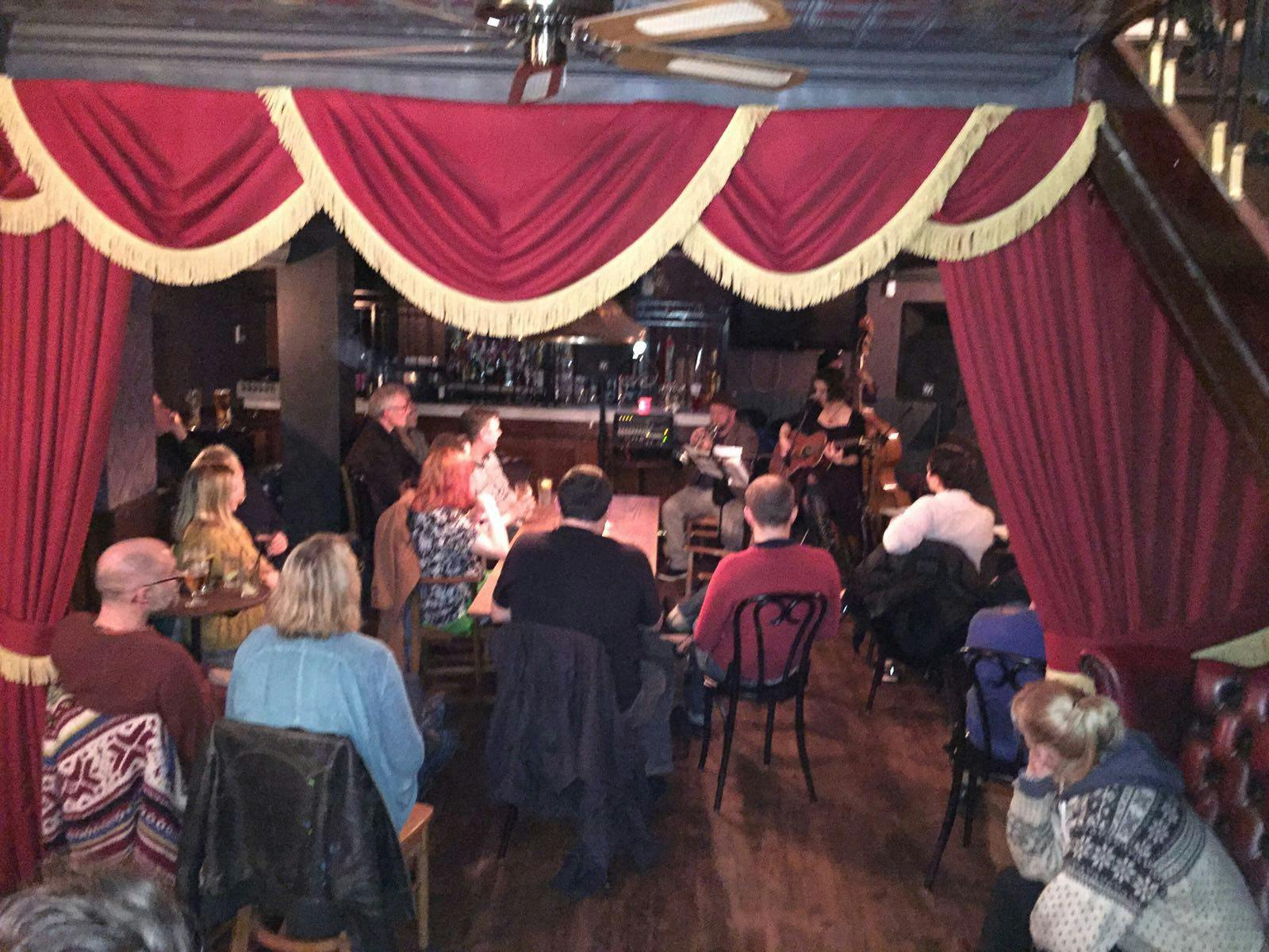 Intimate Rum and Rumour Kabaret Bar with red curtains for live performances and events.