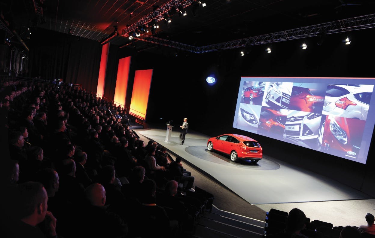 Sleek car on stage at Magna Science Centre product launch event with dynamic visuals.