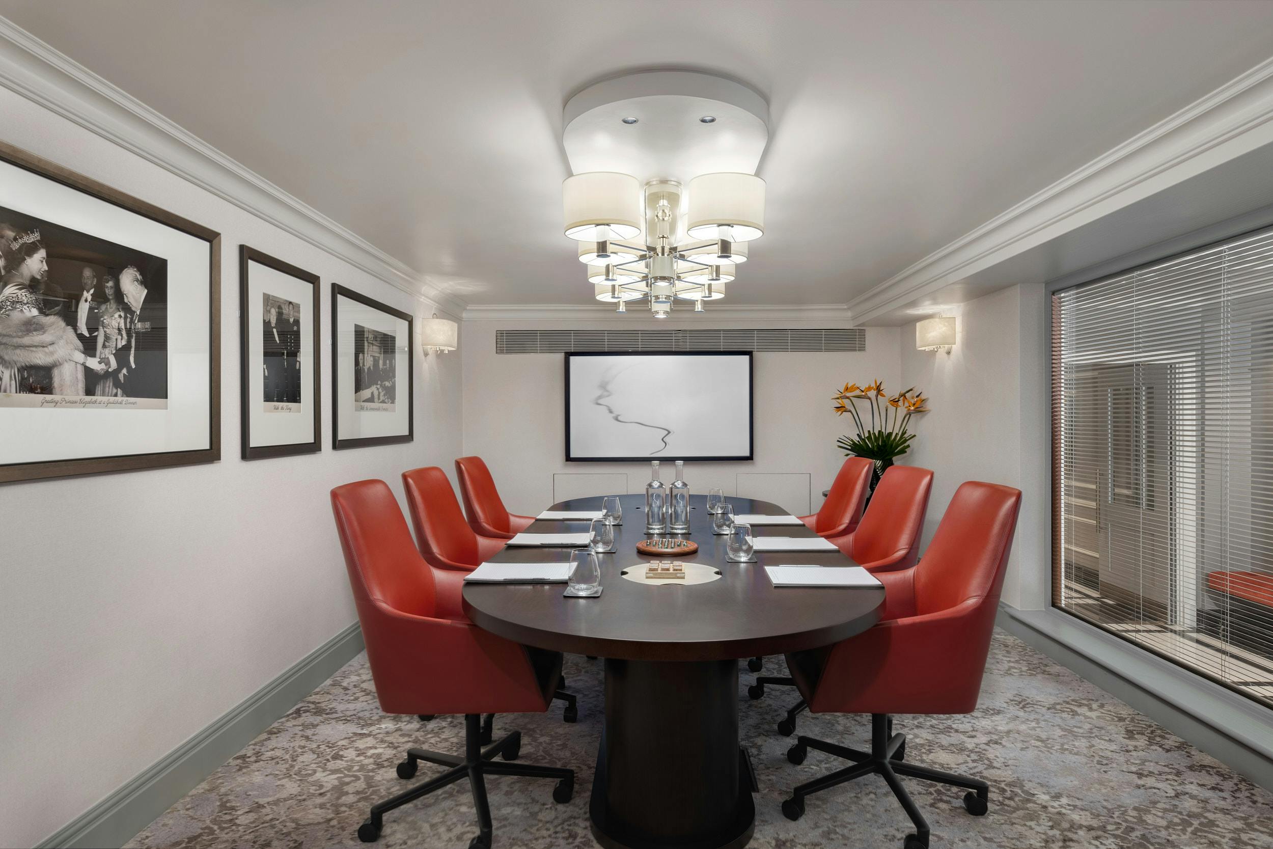 Modern conference room with oval table and red chairs at Hyatt Regency London.