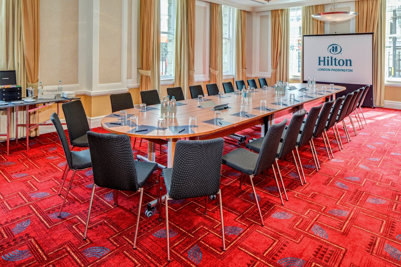 Meeting room at Hilton London Paddington with large table, ideal for corporate events.