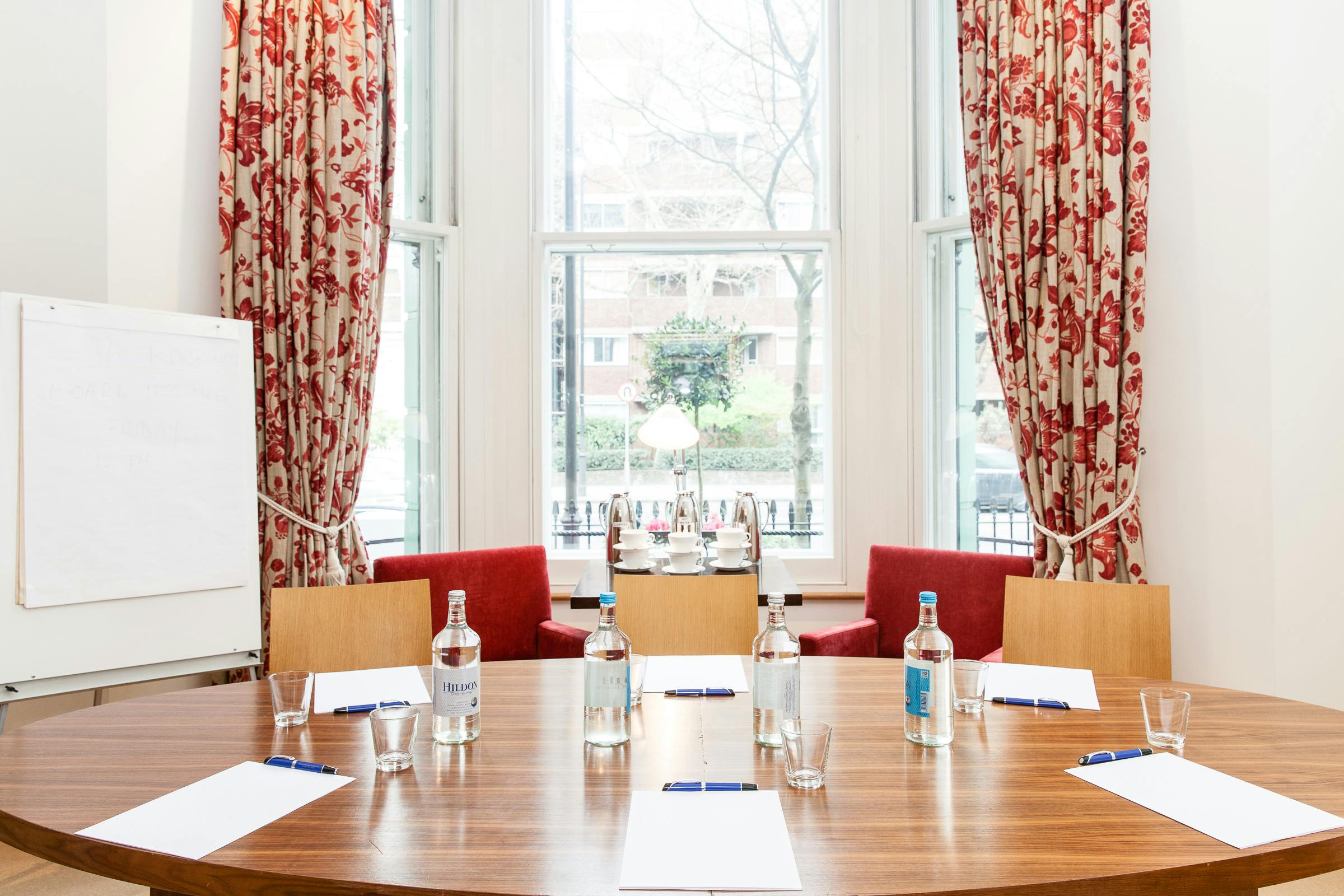 Meeting room with round table and natural light, ideal for corporate events and brainstorming.