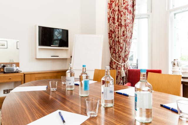 Meeting room with round table, water bottles, ideal for presentations and brainstorming.
