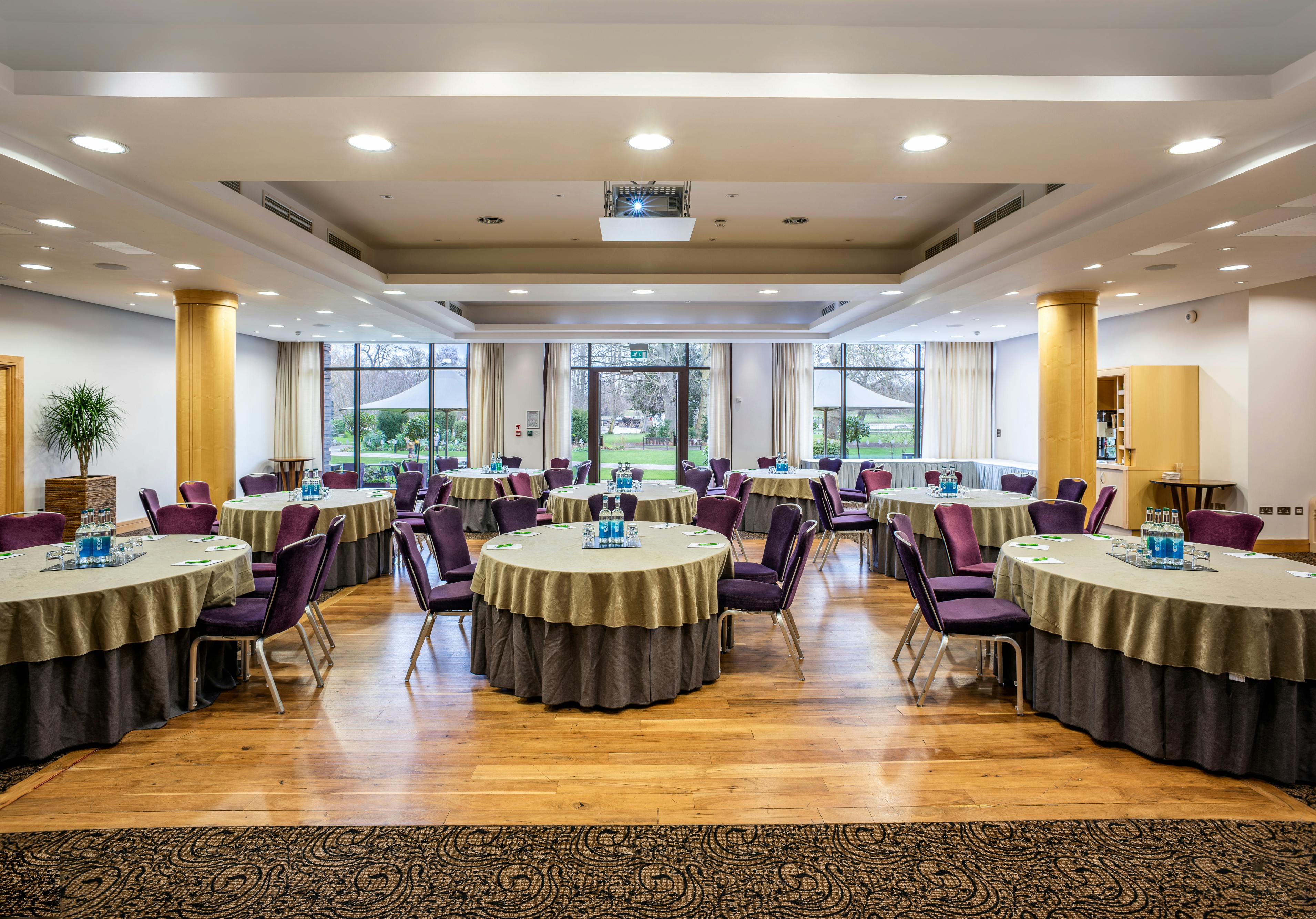 Wimbledon Room at The Lensbury: elegant meeting space with round tables and natural light.