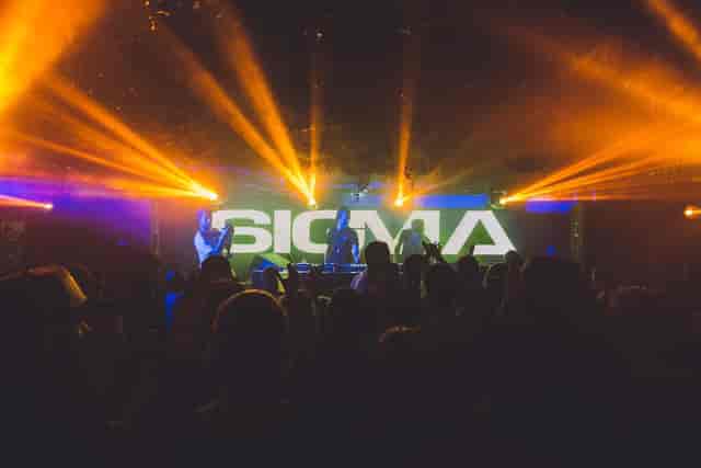 DJ performance at The Bomb Factory, Osea Island, with vibrant lighting and engaged crowd.