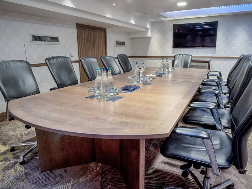 Boardroom 1 at Hilton London Kensington, featuring an oval table for meetings and presentations.