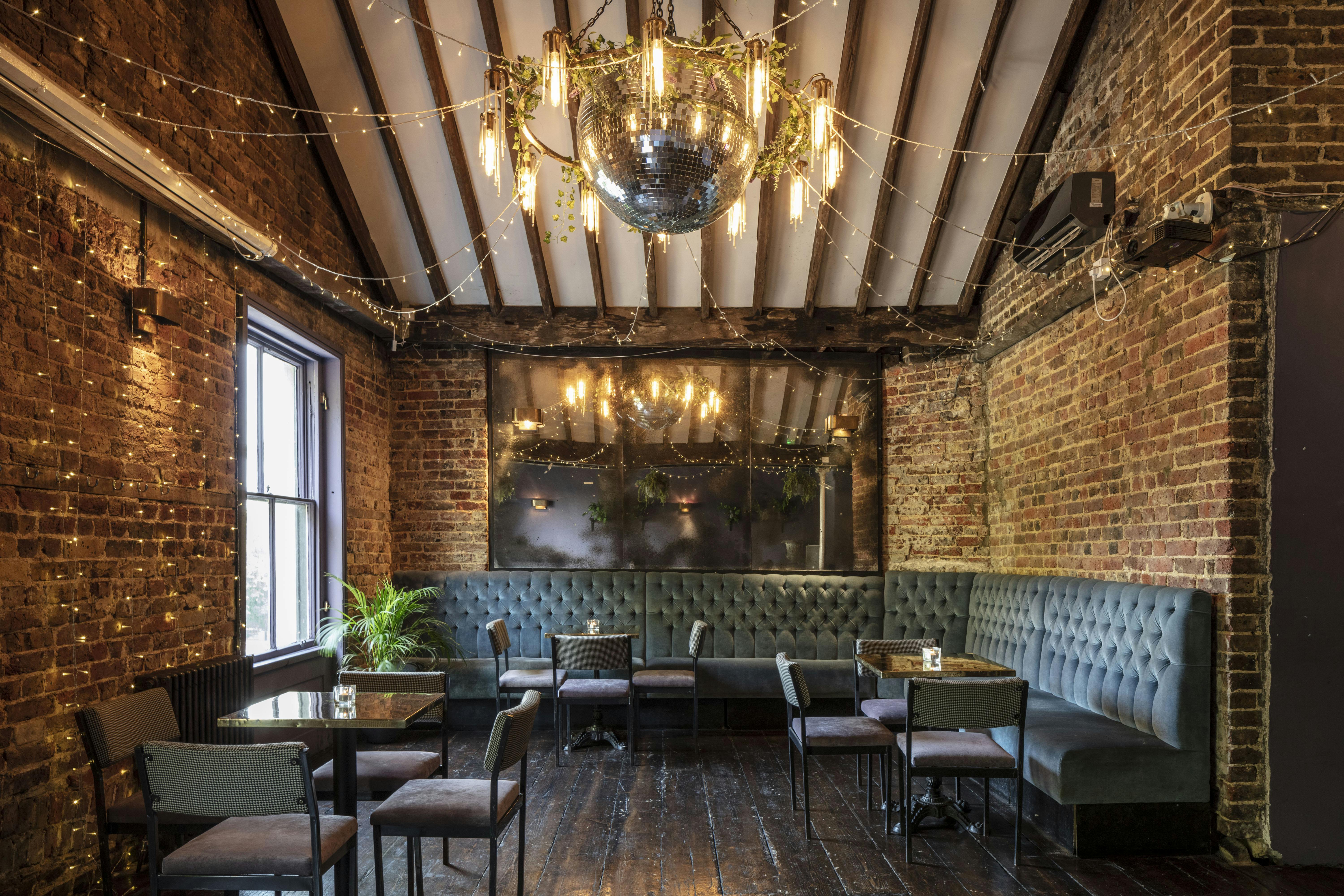 Stylish event space with exposed brick and chandelier, ideal for cocktail receptions.