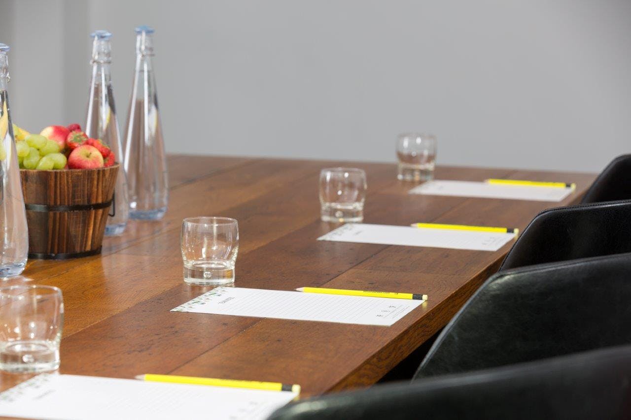 Meeting room at Hotel Football with polished table, water, and notepads for events.