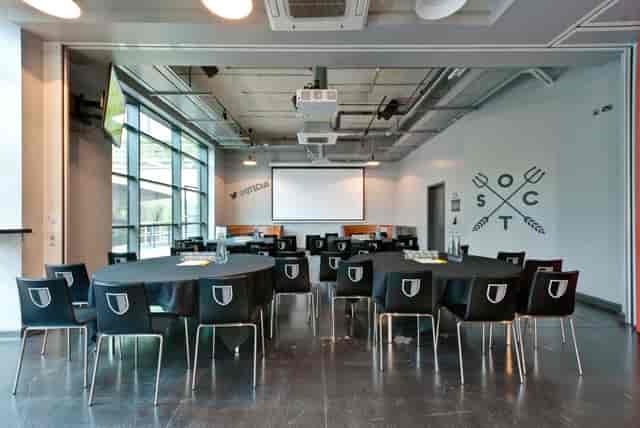 Old Trafford Supporters Club meeting space with round tables, ideal for corporate events.