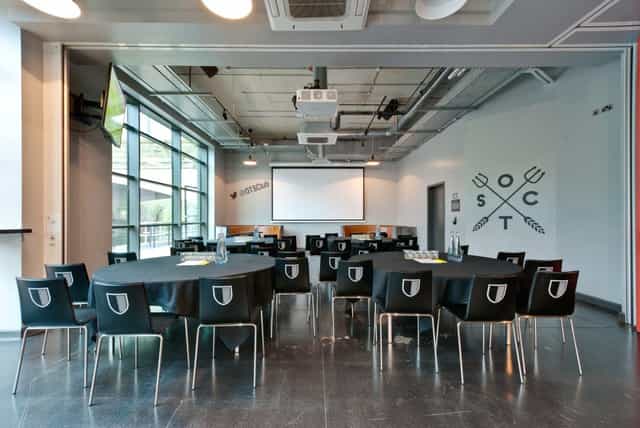 Old Trafford Supporters Club meeting space with round tables, ideal for corporate events.
